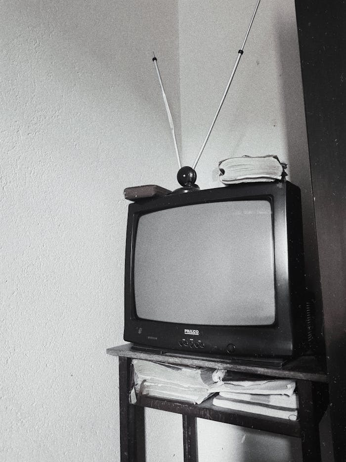 Black and white image of an old television with antenna on a stand.